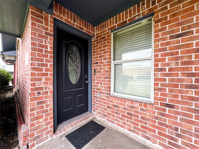 doorway to property featuring brick siding