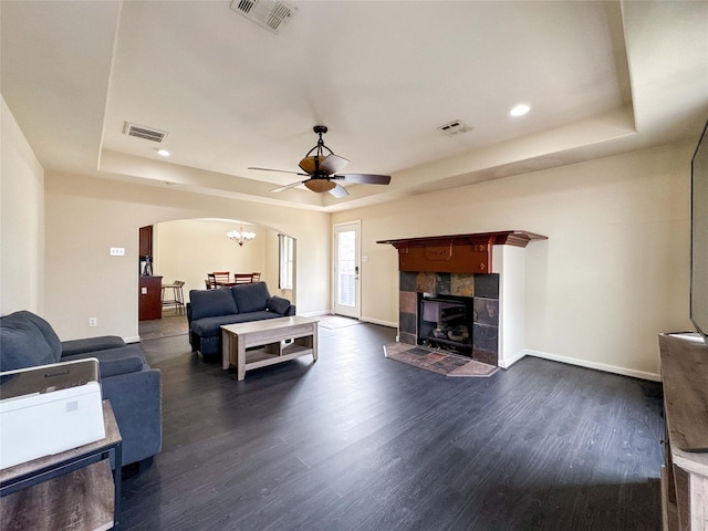 living room featuring a tray ceiling, arched walkways, and visible vents