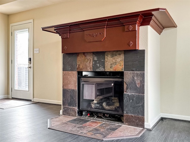 interior details with baseboards, wood finished floors, and a tiled fireplace