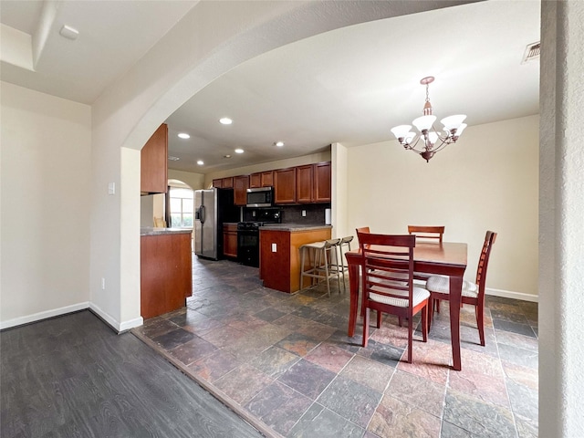 dining room with visible vents, arched walkways, baseboards, and stone tile flooring