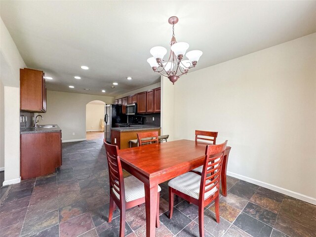 dining area featuring stone finish flooring, baseboards, recessed lighting, arched walkways, and a notable chandelier