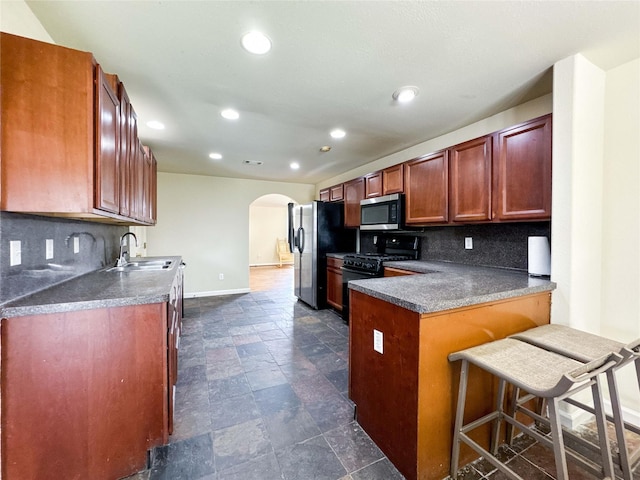 kitchen featuring arched walkways, a sink, stainless steel appliances, and tasteful backsplash