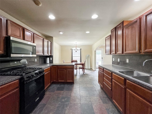 kitchen with gas stove, stainless steel microwave, dark countertops, and a sink