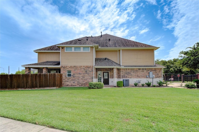 rear view of house featuring brick siding, a shingled roof, fence, cooling unit, and a yard