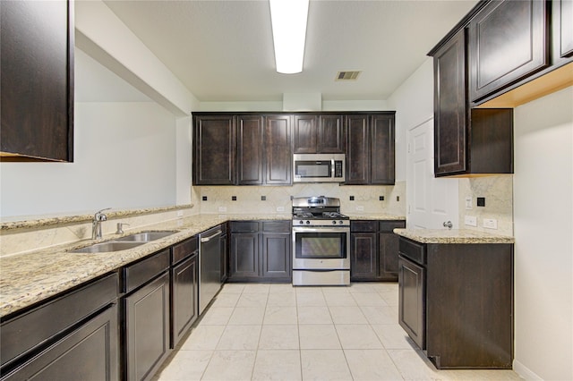 kitchen with visible vents, a sink, stainless steel appliances, light stone countertops, and dark brown cabinets