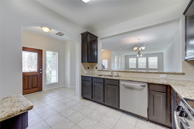 kitchen with dark brown cabinets, a chandelier, appliances with stainless steel finishes, arched walkways, and a sink