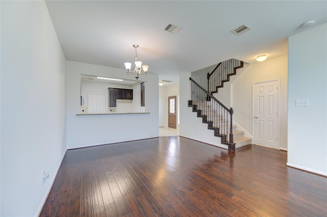 unfurnished living room with visible vents, baseboards, stairway, hardwood / wood-style floors, and a notable chandelier