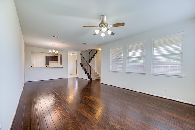 unfurnished living room with visible vents, baseboards, stairway, ceiling fan with notable chandelier, and dark wood-style flooring