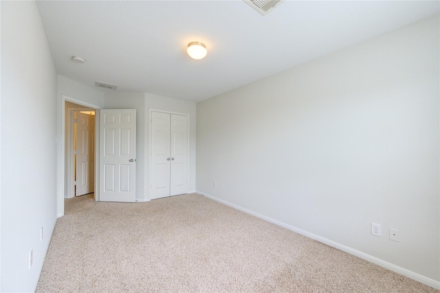 unfurnished bedroom featuring light colored carpet, visible vents, a closet, and baseboards