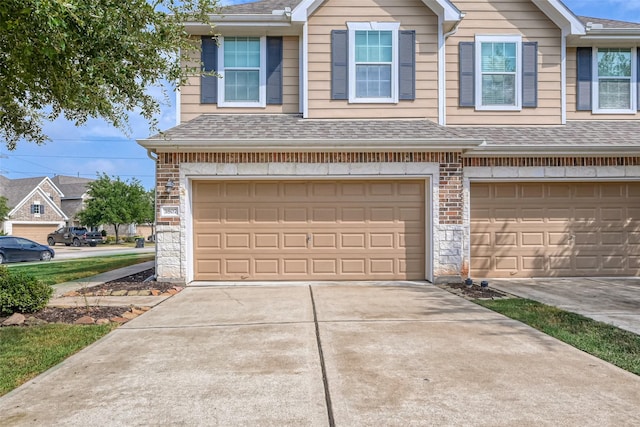 exterior space featuring concrete driveway, a shingled roof, and a garage