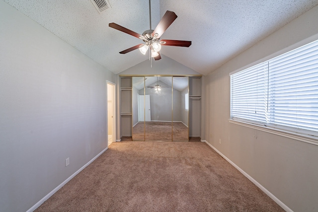 unfurnished bedroom featuring visible vents, lofted ceiling, a textured ceiling, and carpet floors