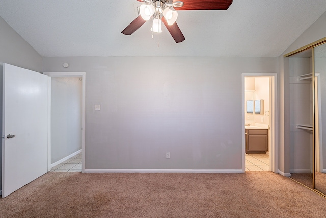 unfurnished bedroom featuring light carpet, connected bathroom, a textured ceiling, and lofted ceiling