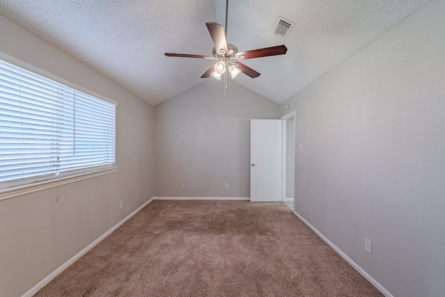 carpeted empty room with visible vents, lofted ceiling, a textured ceiling, and ceiling fan