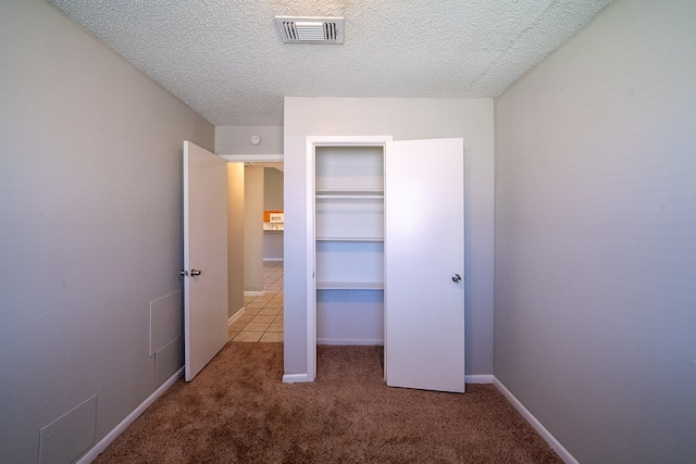 unfurnished bedroom with visible vents, baseboards, carpet, and a textured ceiling