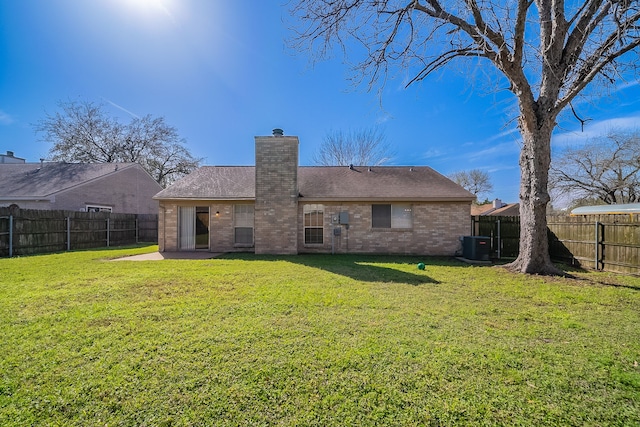 back of property with a yard, brick siding, and a fenced backyard