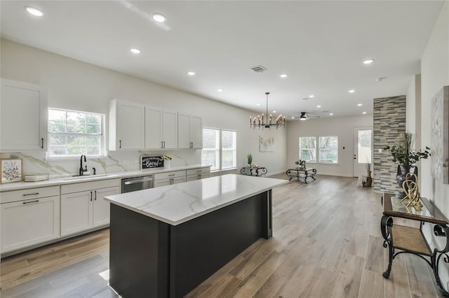 kitchen featuring light wood-style flooring, a sink, a kitchen island, tasteful backsplash, and dishwasher