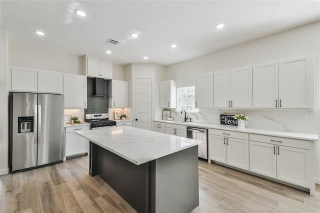 kitchen with visible vents, light wood-type flooring, stainless steel appliances, white cabinetry, and a sink