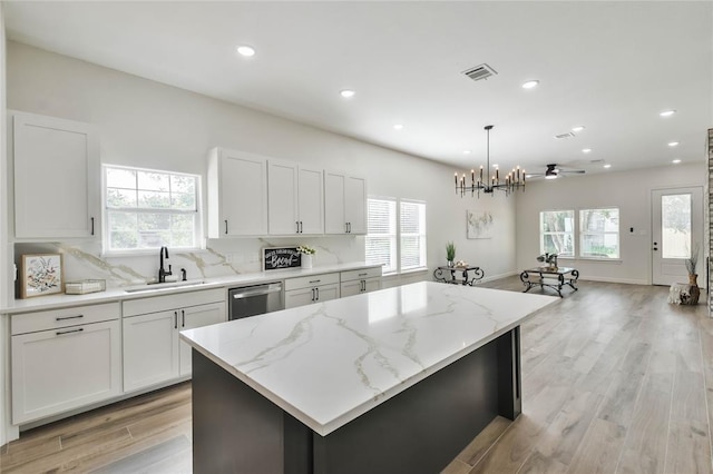 kitchen with visible vents, a sink, tasteful backsplash, a center island, and dishwasher