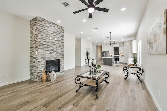 living area featuring a tiled fireplace, light wood-style flooring, recessed lighting, and visible vents