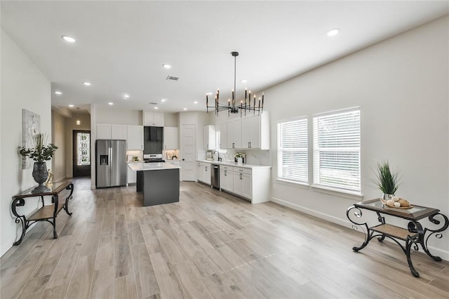 kitchen featuring light countertops, white cabinets, a center island, and stainless steel appliances