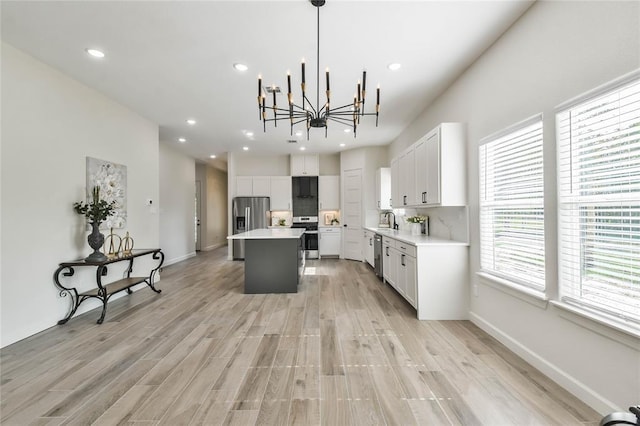 kitchen with tasteful backsplash, a center island, light countertops, light wood-style flooring, and appliances with stainless steel finishes