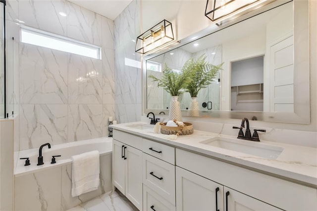 bathroom featuring double vanity, marble finish floor, a garden tub, and a sink