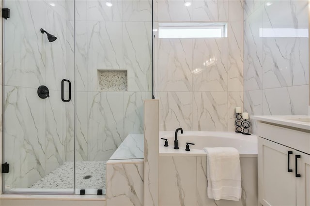 full bathroom with vanity, a garden tub, and a marble finish shower