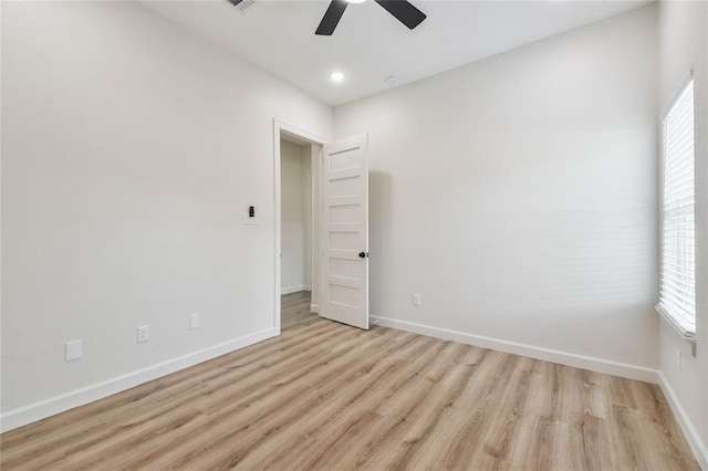 spare room with light wood finished floors, a ceiling fan, baseboards, and a wealth of natural light