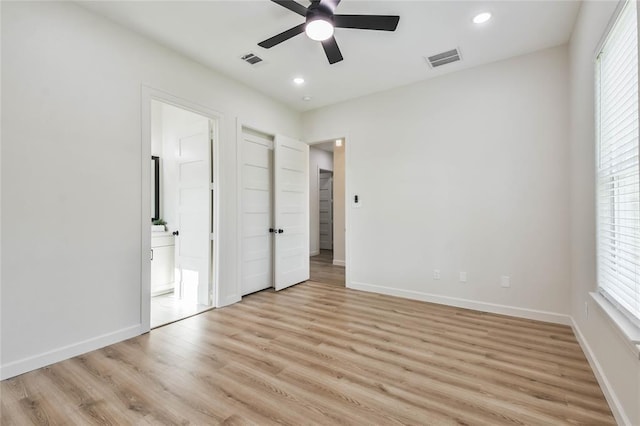 unfurnished bedroom with light wood-type flooring, visible vents, multiple windows, and baseboards