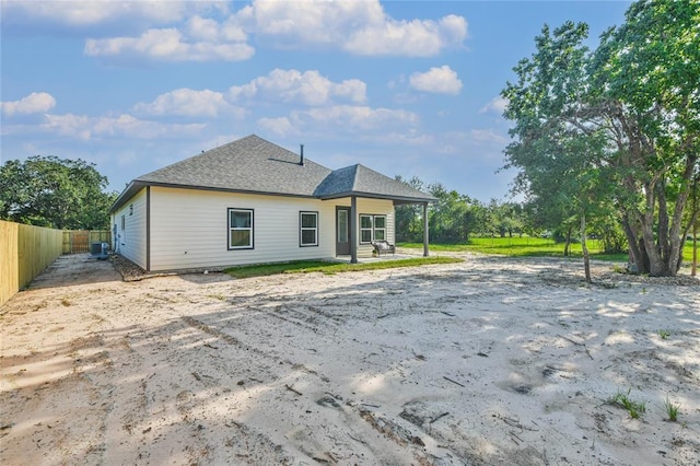 rear view of house featuring fence and a shingled roof