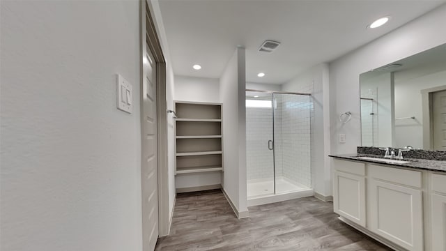 bathroom featuring recessed lighting, vanity, wood finished floors, and a shower stall