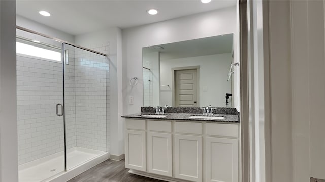 bathroom with double vanity, a shower stall, wood finished floors, and a sink