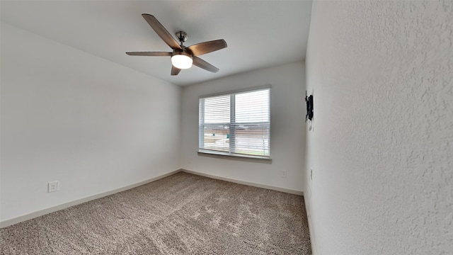 carpeted spare room with a ceiling fan and baseboards