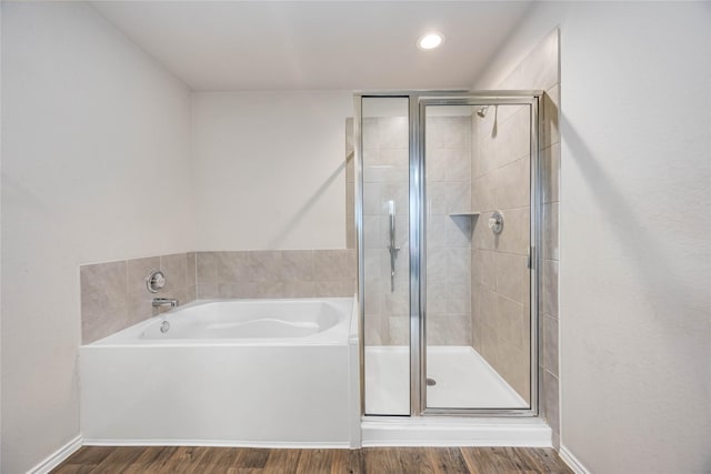 full bath with a bath, wood finished floors, a stall shower, and baseboards