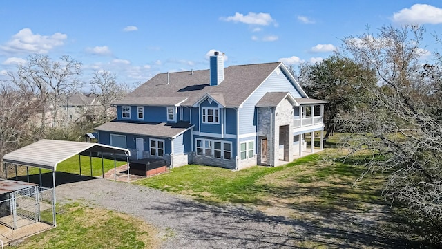 rear view of property with driveway, a shingled roof, a chimney, a carport, and a lawn