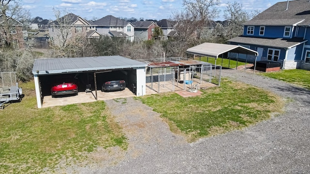 view of yard with a residential view, a detached carport, and driveway