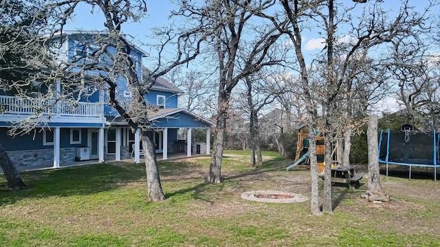 view of yard featuring a fire pit, a playground, and a trampoline