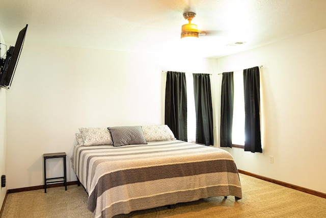 bedroom with visible vents, light colored carpet, baseboards, and ceiling fan