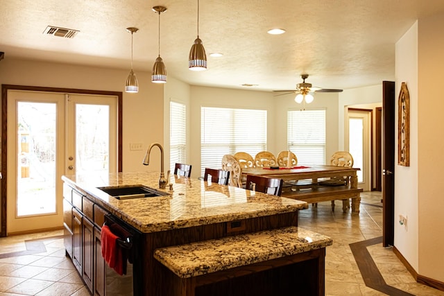 kitchen featuring dishwasher, a textured ceiling, visible vents, and a sink