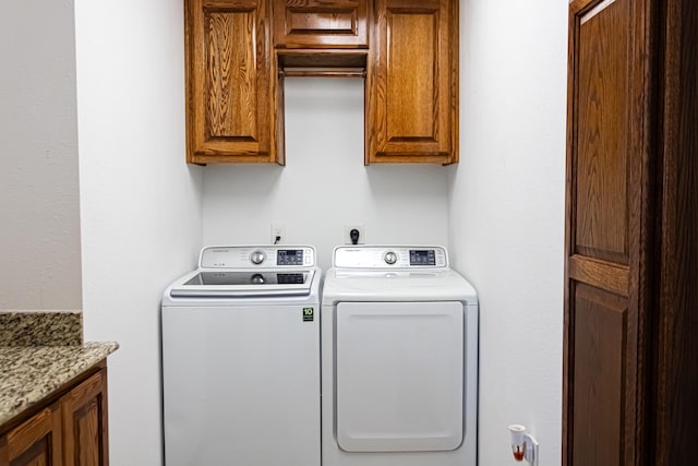 clothes washing area featuring cabinet space and washing machine and dryer