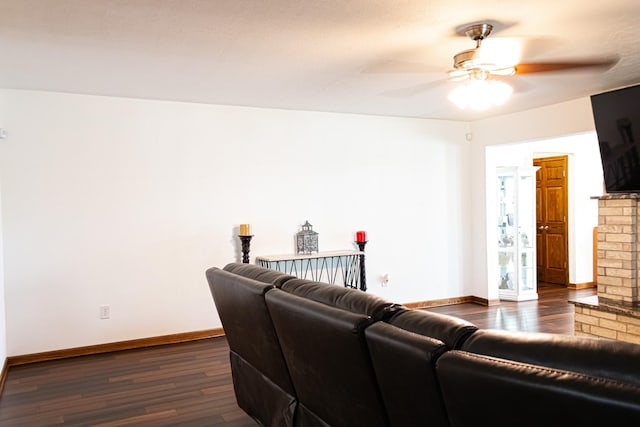 living room with baseboards, dark wood-type flooring, and a ceiling fan