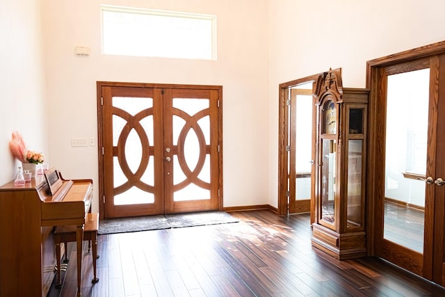 entryway with dark wood-style floors, french doors, baseboards, and a towering ceiling