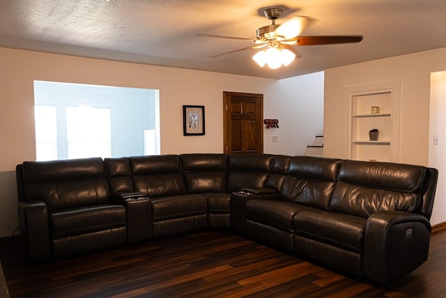 living area featuring built in shelves, a textured ceiling, a ceiling fan, and dark wood-style flooring