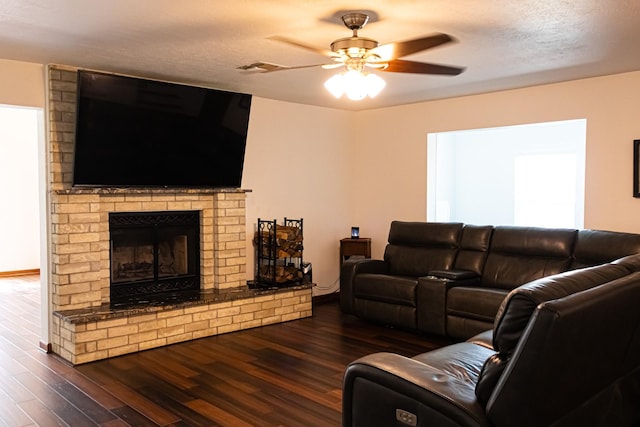 living room featuring wood finished floors, visible vents, a ceiling fan, a fireplace, and a textured ceiling