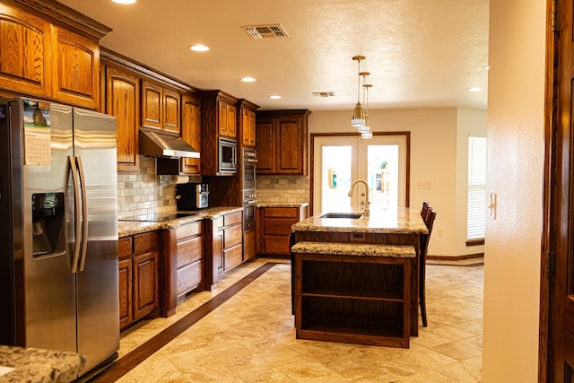 kitchen with visible vents, a sink, decorative backsplash, stainless steel appliances, and under cabinet range hood