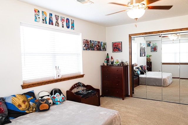 bedroom featuring a ceiling fan, visible vents, a closet, and light carpet