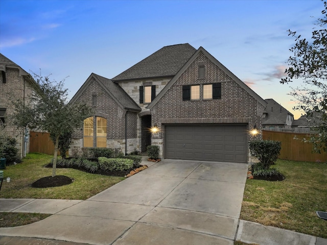 view of front of property with fence, driveway, stone siding, a lawn, and brick siding