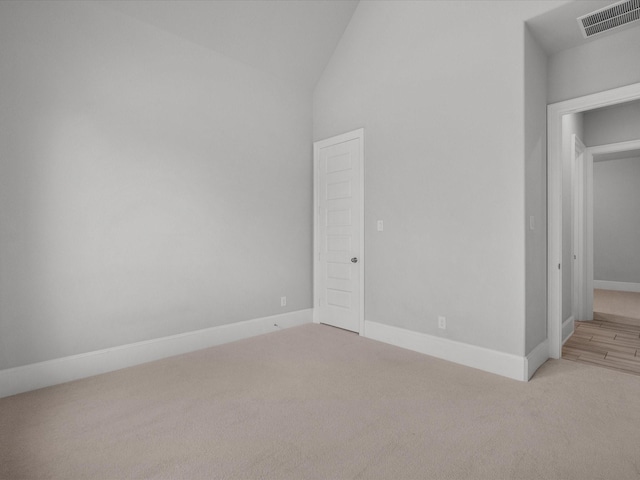 empty room with visible vents, carpet flooring, baseboards, and lofted ceiling