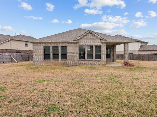 back of property featuring a yard, a fenced backyard, brick siding, and a patio