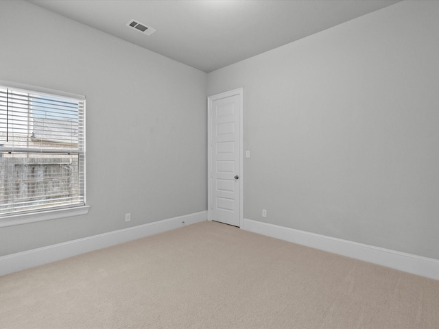 empty room with light carpet, visible vents, and baseboards